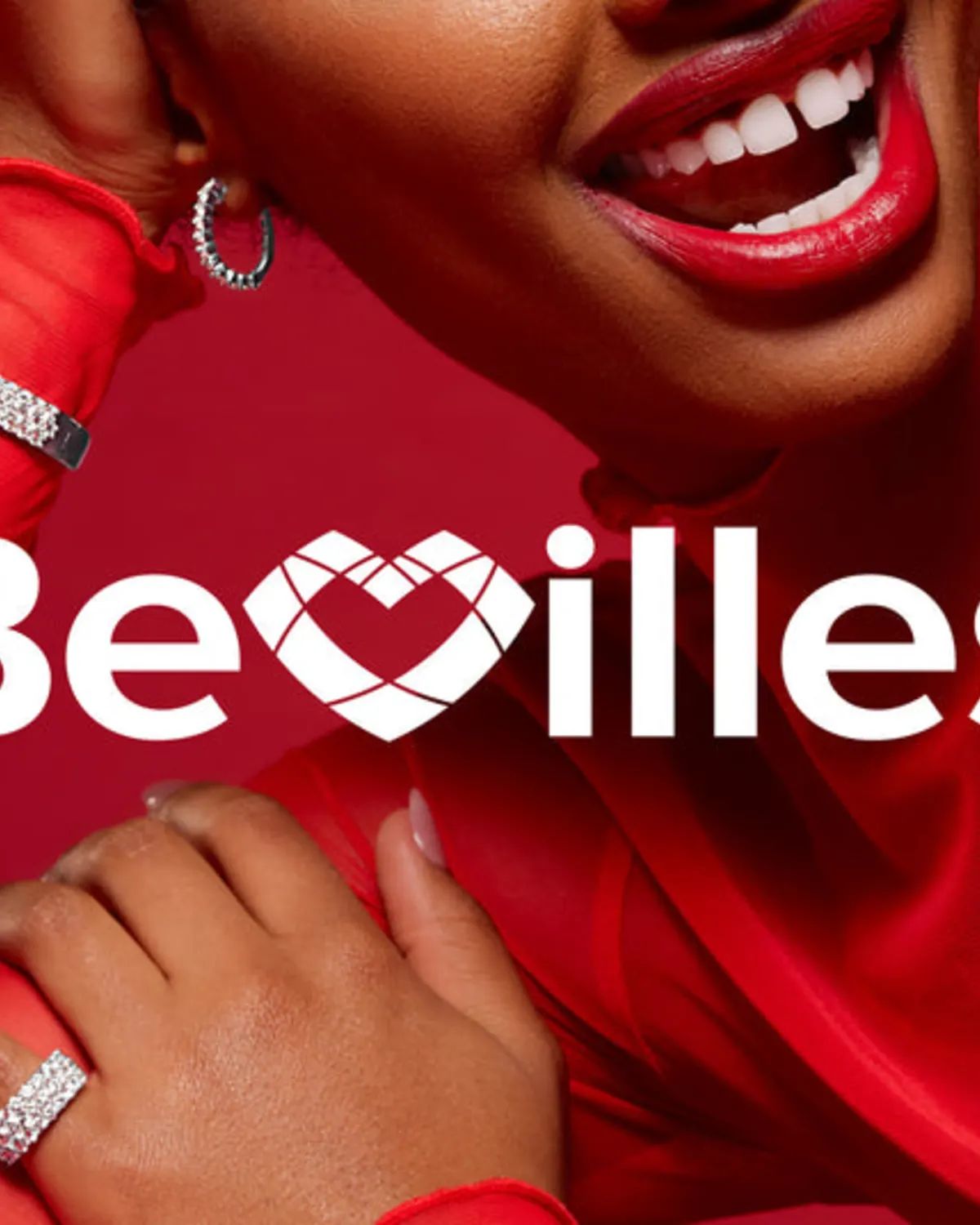 Smiling woman displaying diamond jewellery against a red backdrop
