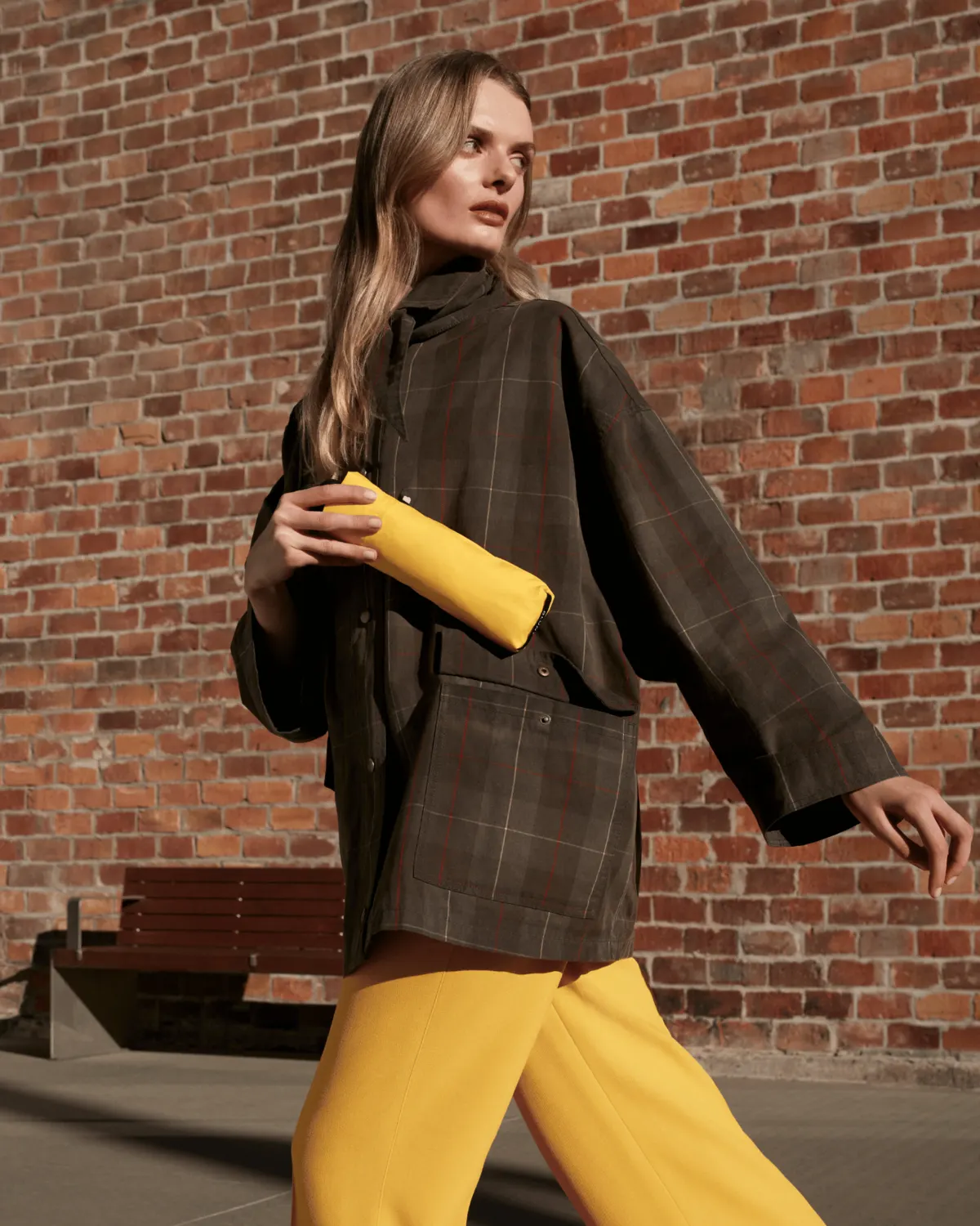 Woman in a raincoat carrying a yellow compact umbrella