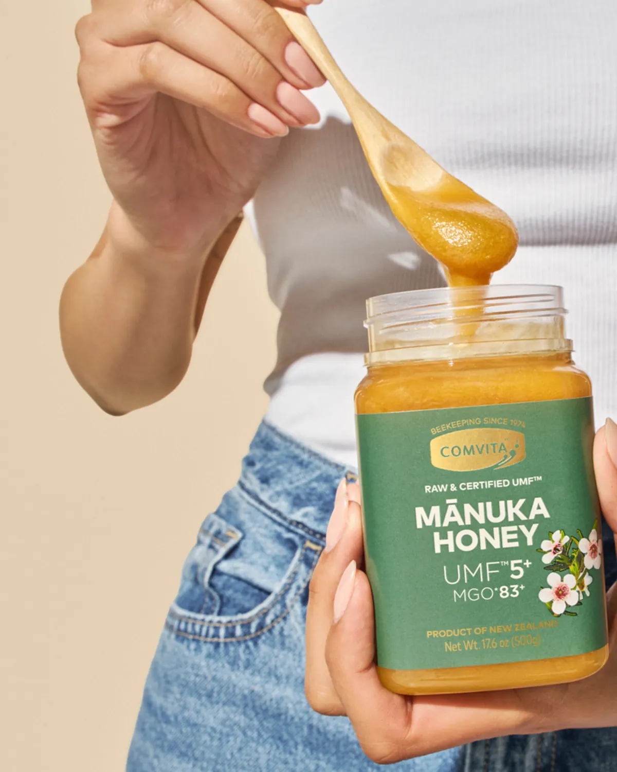 Woman drizzling Comvita Mānuka honey from a wooden spoon