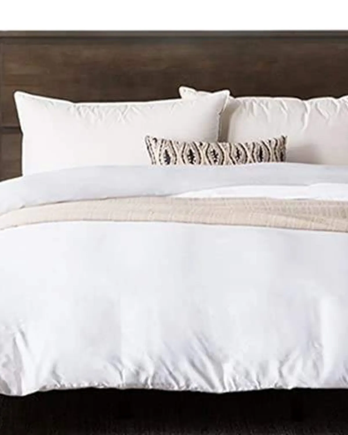 White luxury bedding arranged on a dark wood bed