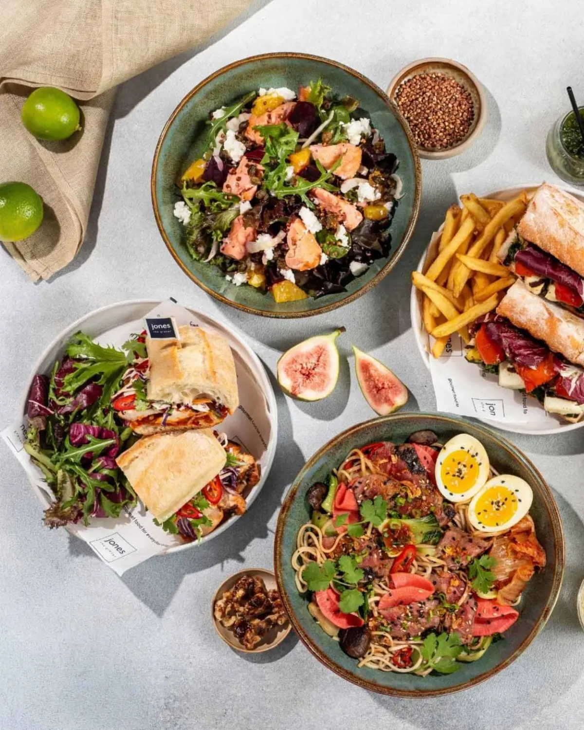 Overhead spread of colourful salads, sandwiches and noodles