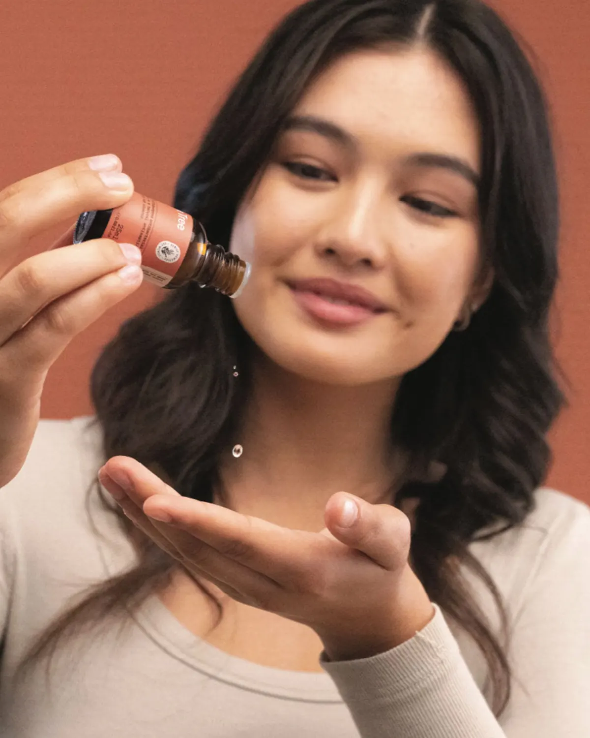 Woman dispensing liquid drops from an amber bottle into her palm