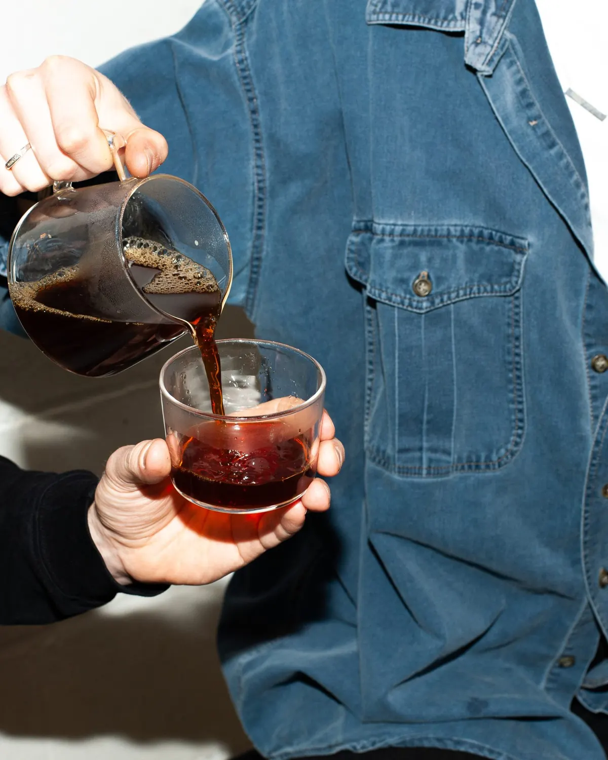 Fresh coffee poured from a glass carafe into a tumbler