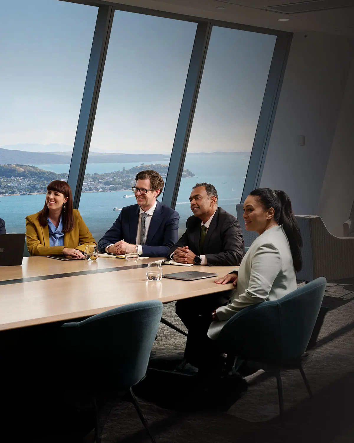 Four colleagues meeting in an office overlooking a coastal harbour