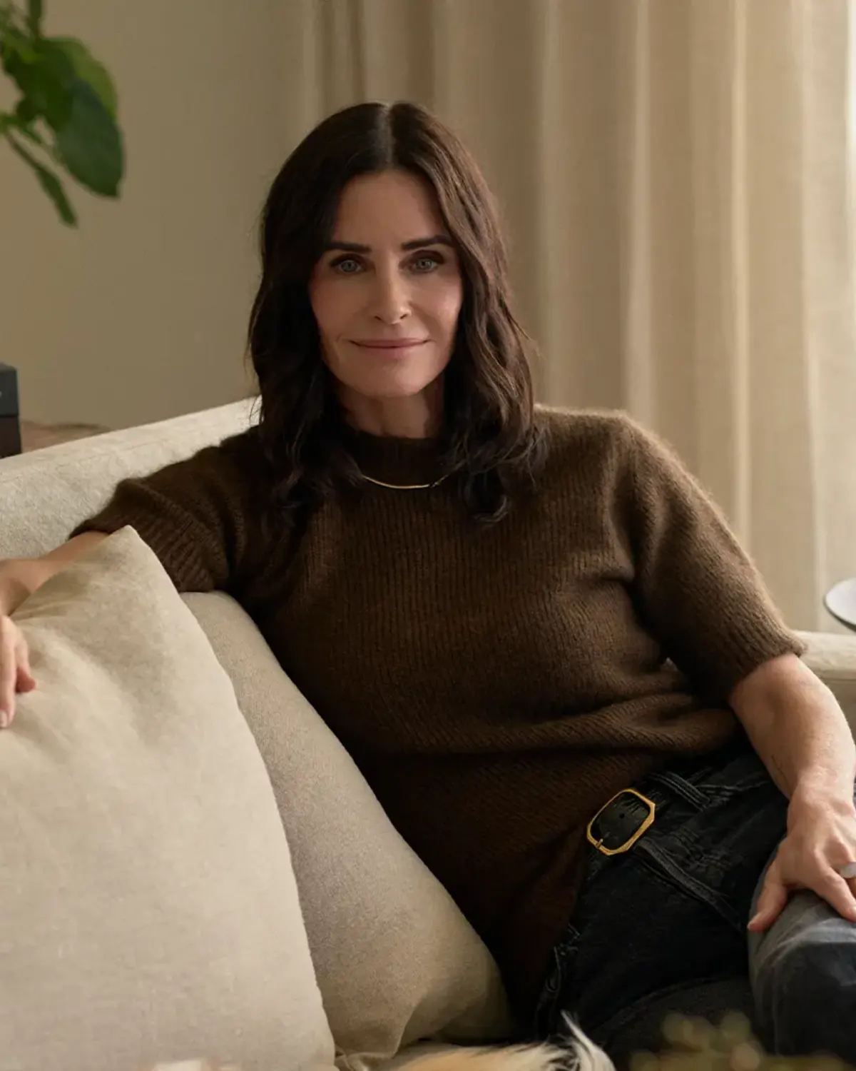 Woman seated on a cream sofa in a softly lit room