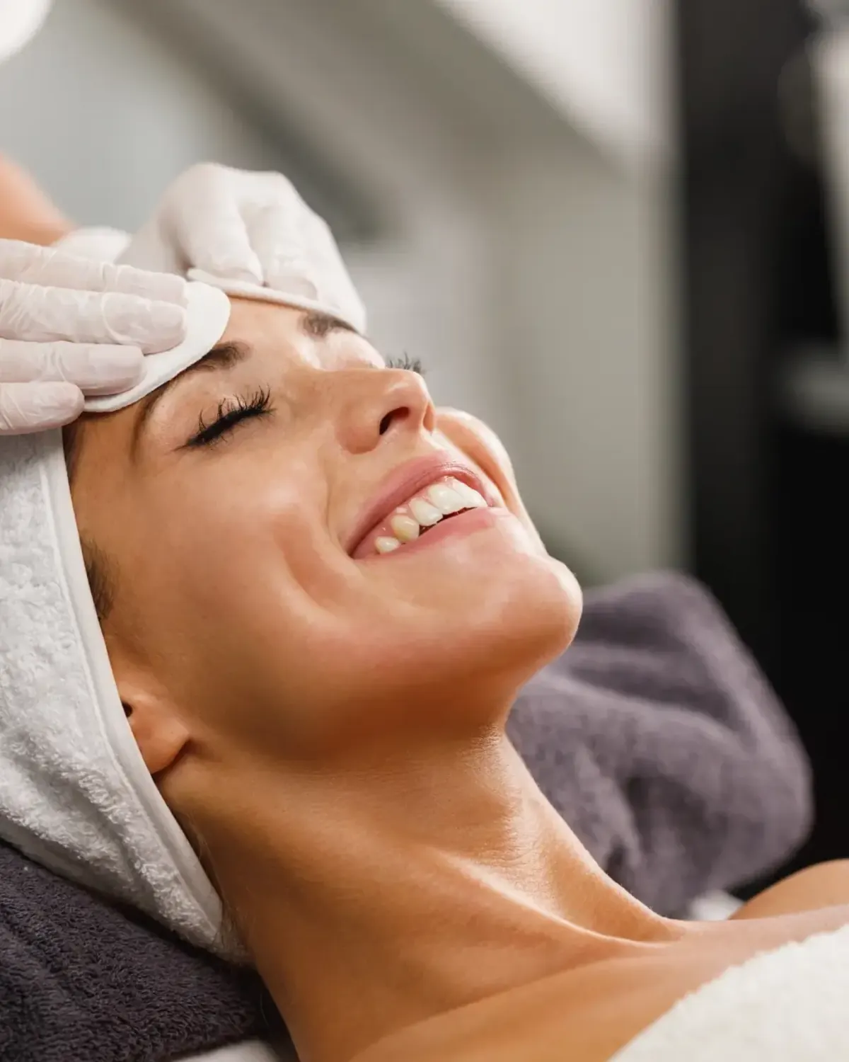 Smiling woman receiving a gentle facial treatment at Quantum Polyclinic