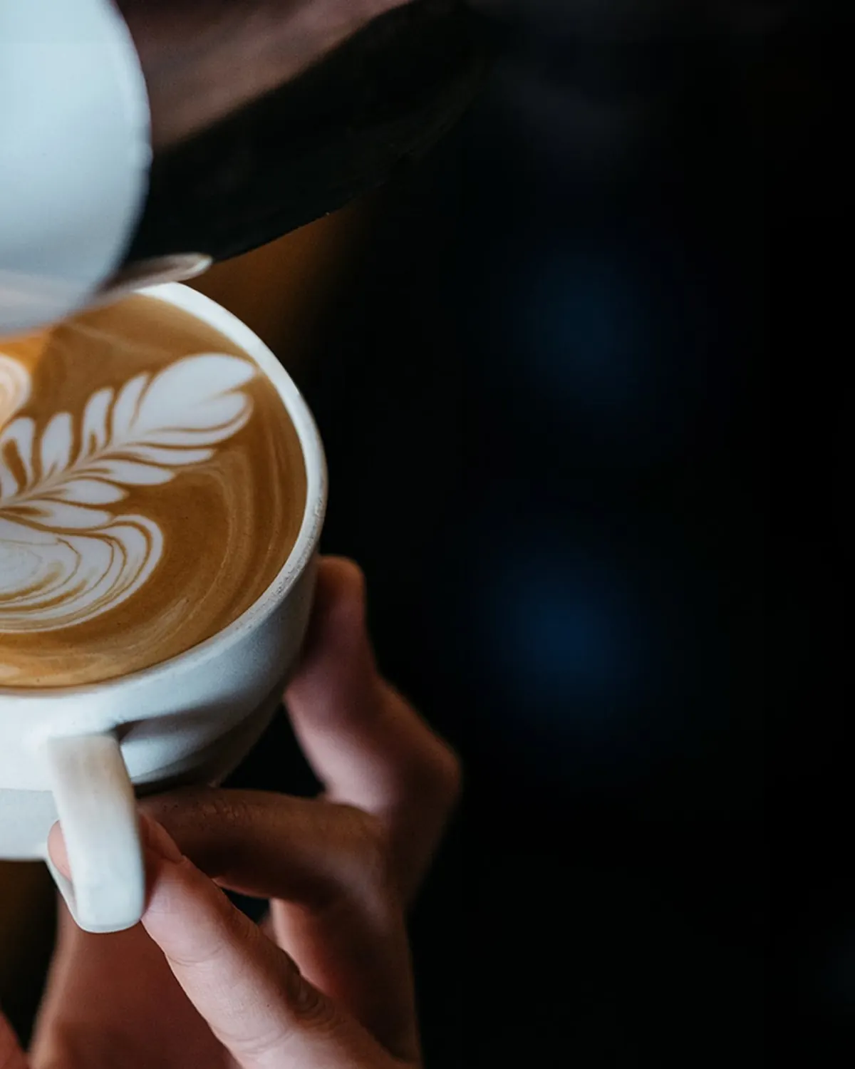 Barista pouring leaf latte art into a coffee cup